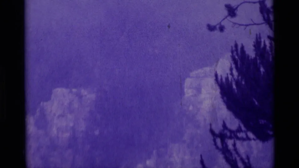 1975 8mm frame from Agate Springs, Montana, with rocky mountain forms softened by grain and a strong purple cast.