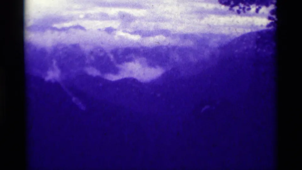 Agate Springs, Montana 8mm frame with hazy mountain ridges, clouds, and dark leaves along the upper edge.