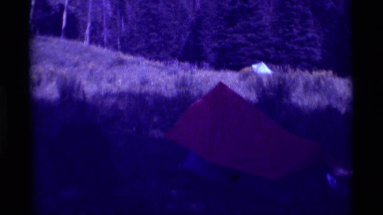 Red tent appears in a grassy field near a tree line in the 1975 Agate Springs, Montana home-movie footage.