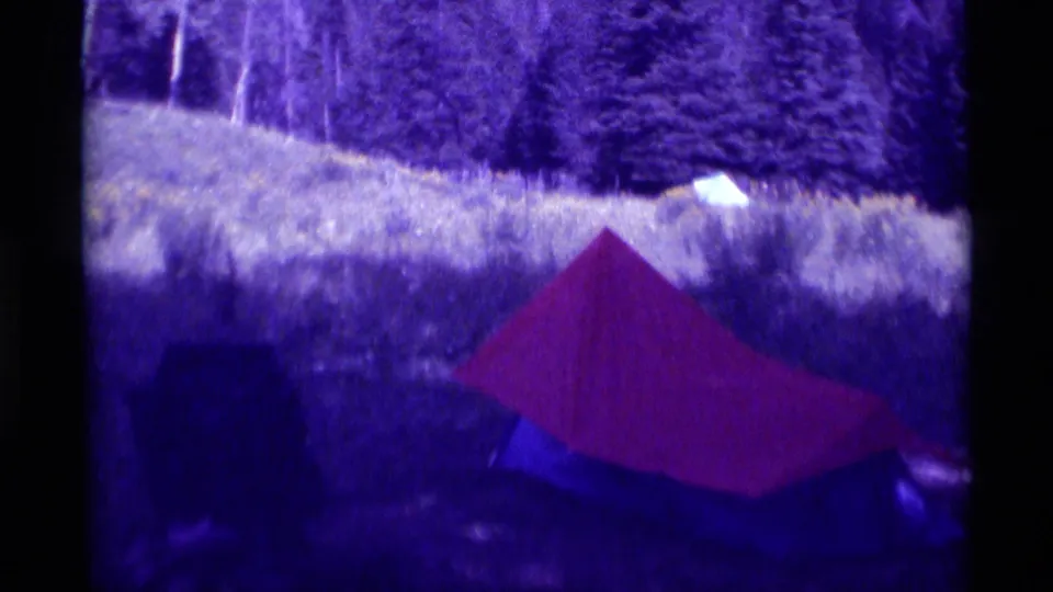 Final frame holds on the red tent in a grassy Montana field, framed by trees and dark 8mm film borders.
