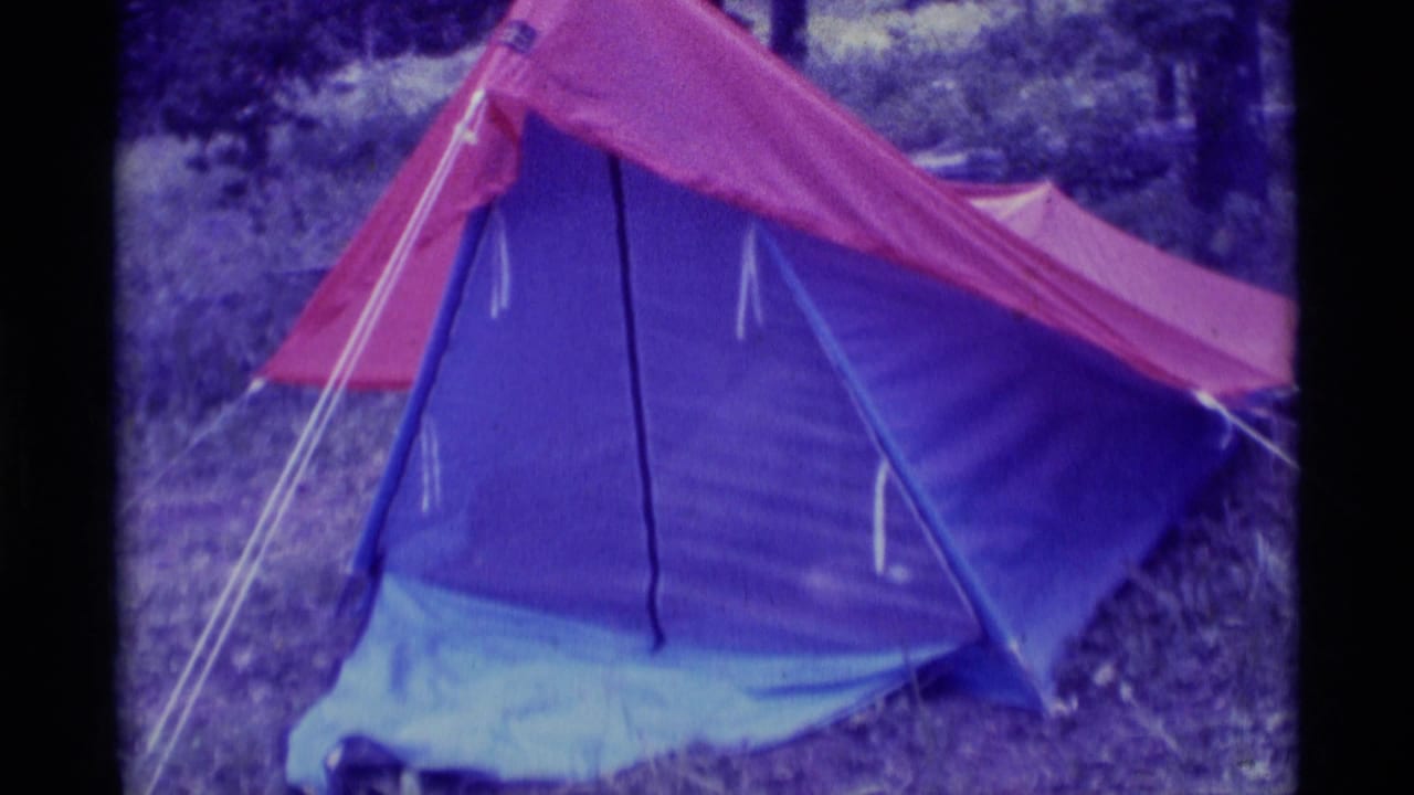 1975 Agate Springs, Montana 8mm frame showing a red and blue tent set in wooded ground with visible guy lines.