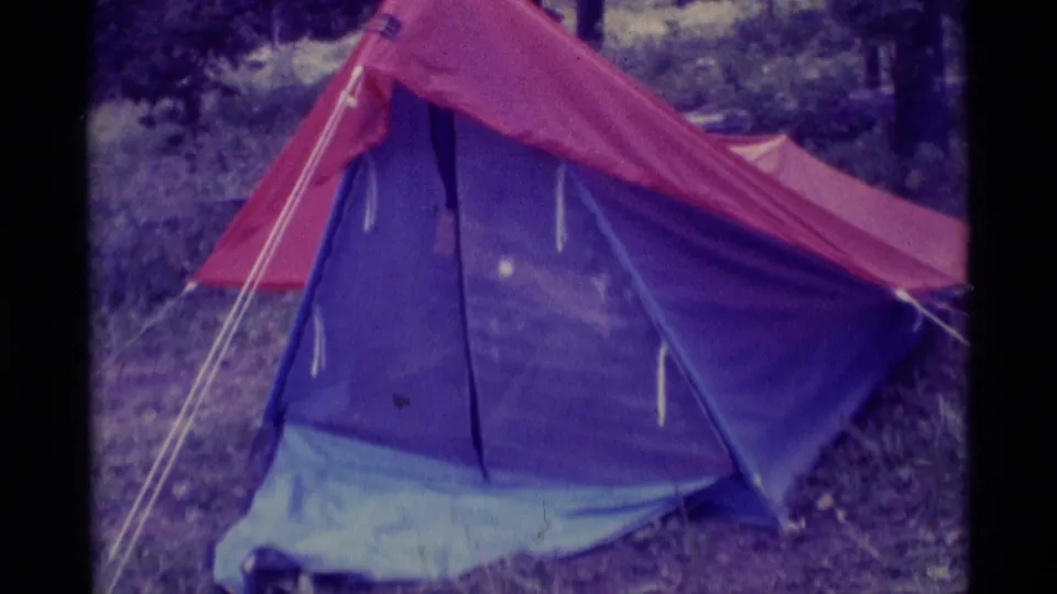 Agate Springs, Montana camping still with the tent flap opened wider, showing a dark interior space and wooded surroundings.