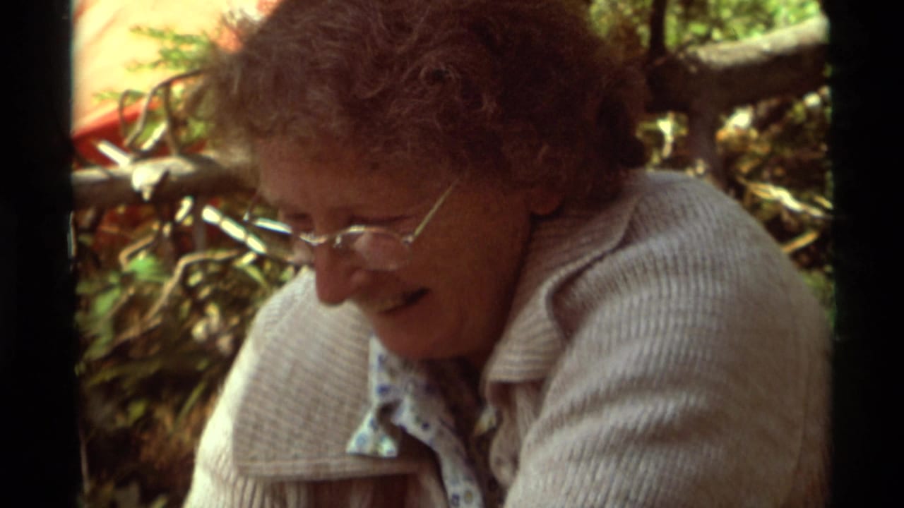Closer view of a woman in glasses leaning over campsite meal preparation.
