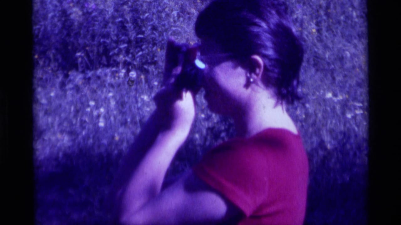 Close 8mm frame of a woman in a red shirt using a scope in the grassy Agate Springs, Montana setting.
