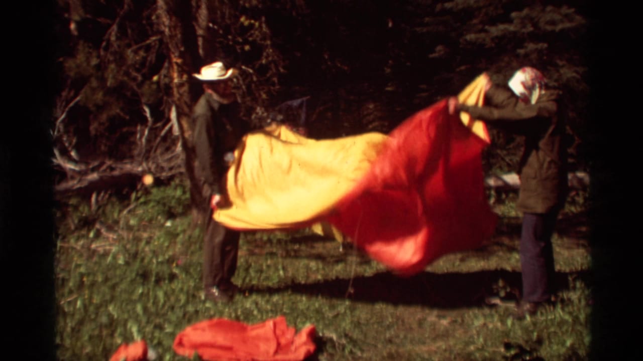Two adult men set up a yellow and red tent in a forested clearing at Agate Springs, Montana, in 1975.