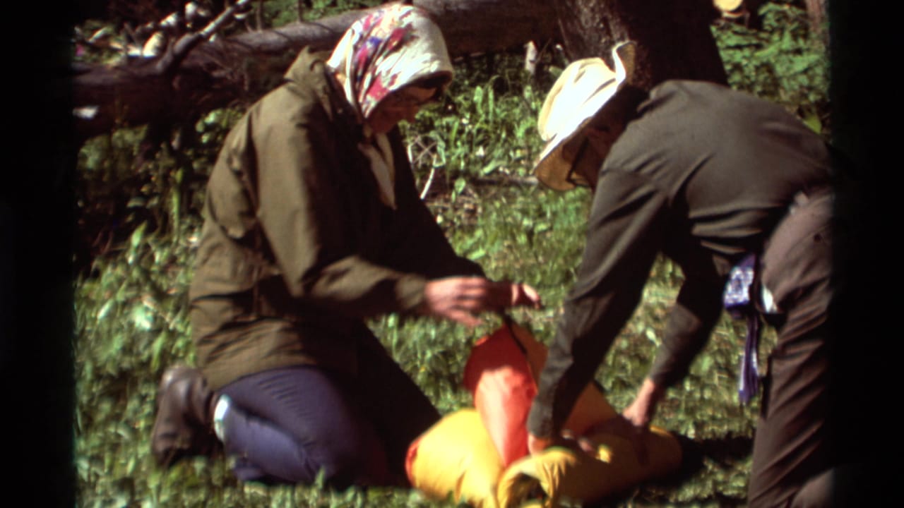 Two older campers in a Montana forest handle bright sleeping bags and hiking gear in handheld 8mm footage from 1975.
