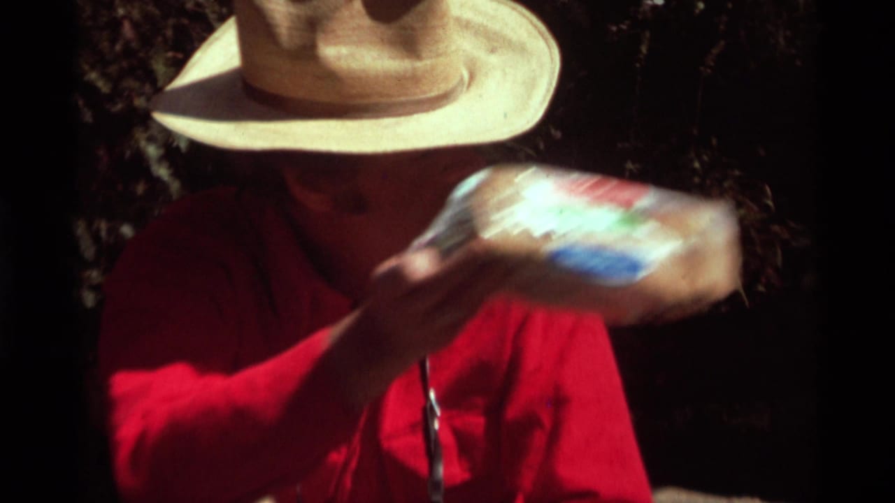 Closer view of the man in a straw hat holding wrapped bread in bright sunlight.