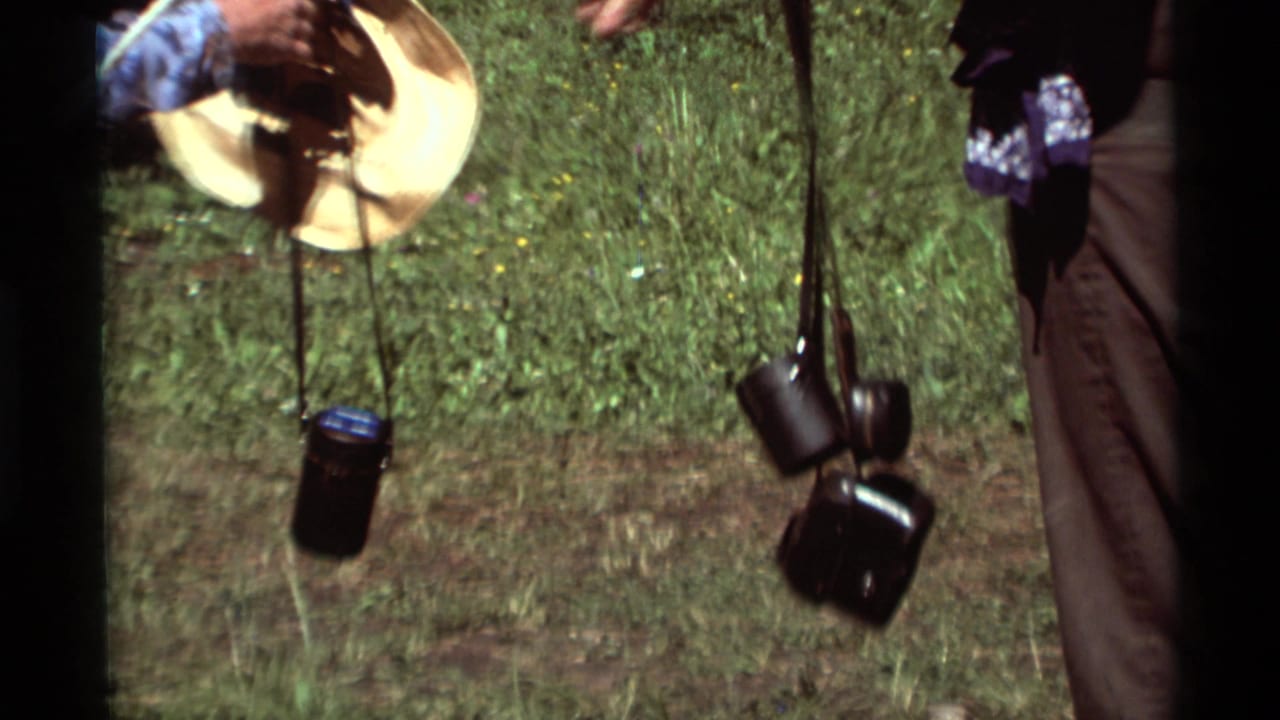 1975 8mm Montana home-movie frame showing a close view of hikers' hanging gear near grass and trees.