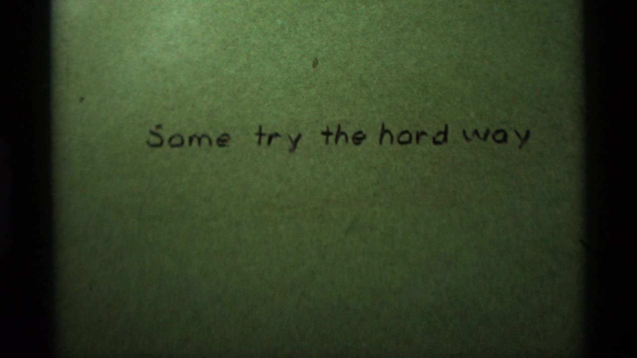 Green-tinted 8mm frame with handwritten title text, soft exposure, and visible film edge shadowing.