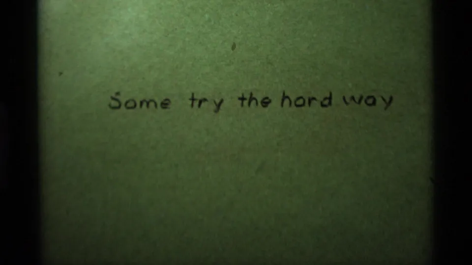 Green-tinted 8mm frame with handwritten title text, soft exposure, and visible film edge shadowing.
