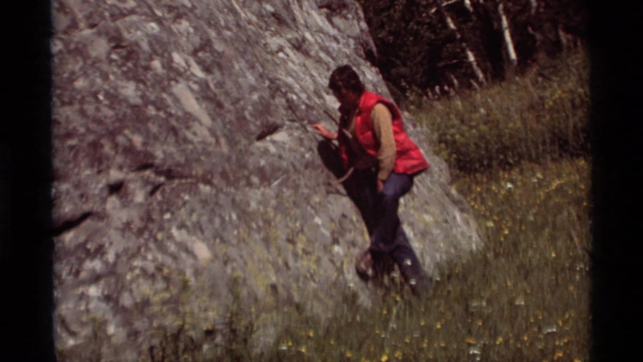 At Agate Springs, Montana in 1975, a person in a red vest stands near a large rock face in an 8mm home-movie frame.