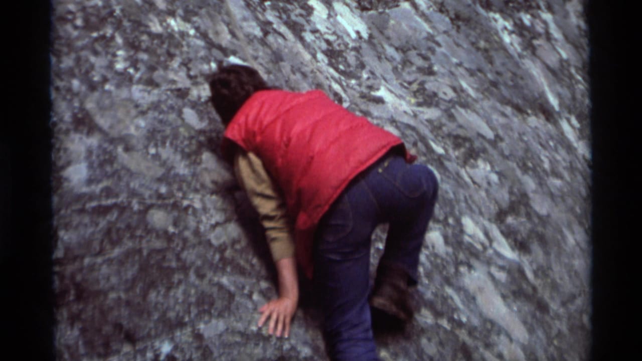 In 1975 Agate Springs, Montana footage, a person in a red vest and blue jeans leans into a steep gray rock face while climbing.