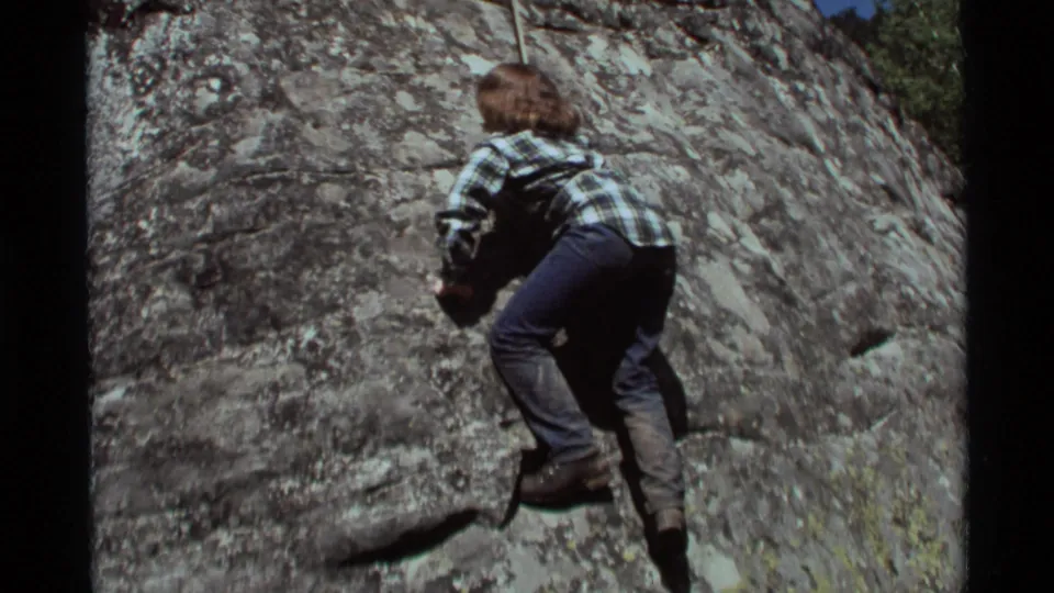 1975 Agate Springs, Montana 8mm frame showing the climber close to the stone, knees bent, with boots planted on small holds.