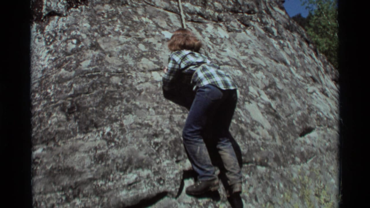 Climber leans into the rock face while holding a rope above the stone.