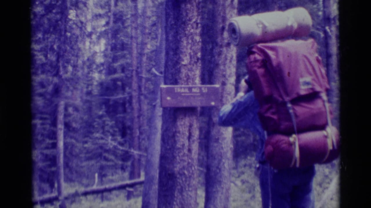 1975 Montana 8mm frame showing a hiker with a large backpack near a wooden Trail No. 51 sign among trees.