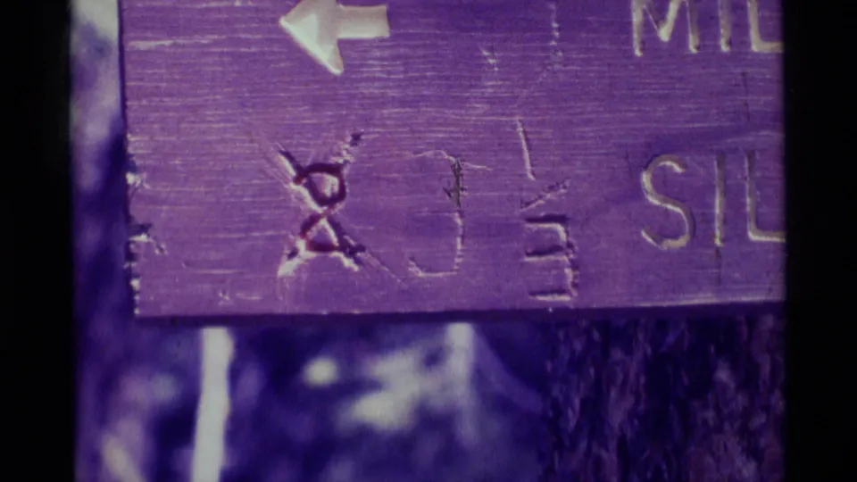 Close 8mm detail of the Trail No. 51 sign, with a left arrow, scratched markings, and partial Silver Pass text visible.
