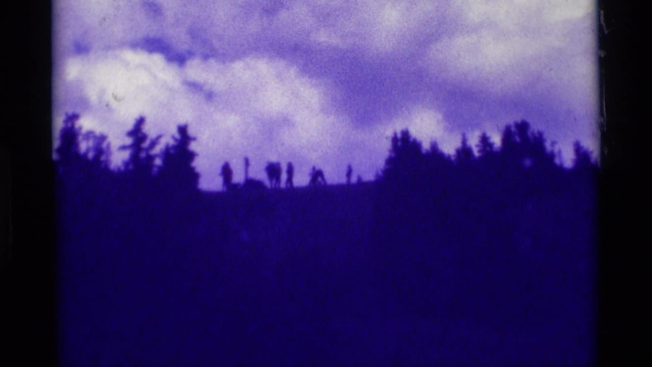 1975 8mm Agate Springs, Montana view of a dark tree-lined ridge silhouetted below large pale clouds.