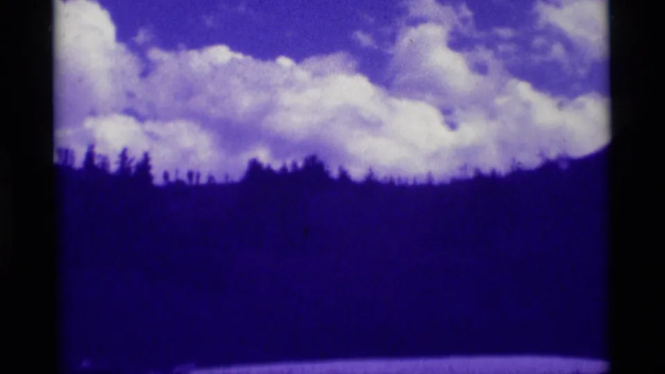 Agate Springs 8mm landscape frame with dark foreground hills, ridge trees, and bright clouds across the upper sky.