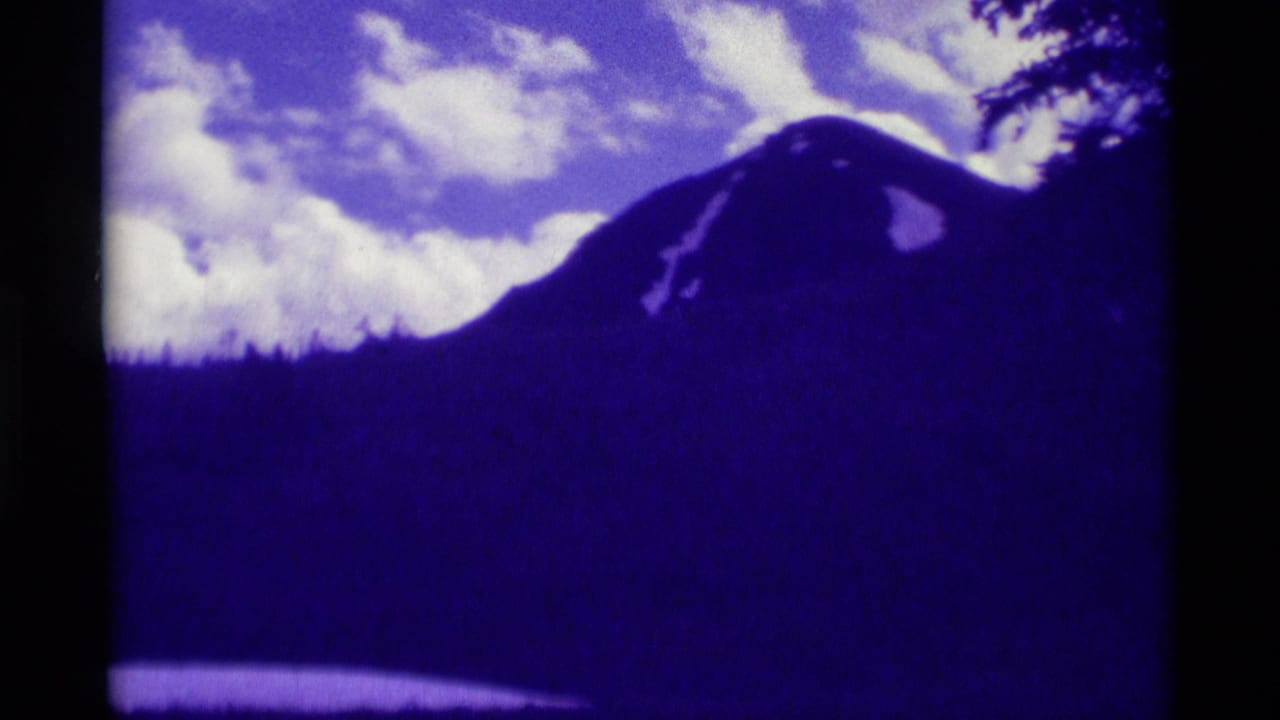 Agate Springs, Montana mountain view with a dark ridge, scattered clouds, and tree silhouettes in purple-shifted 8mm footage.