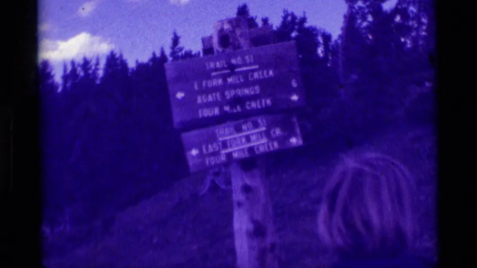 1975 Montana hiking footage showing a wooden Trail No. 51 sign for East Fork Mill Creek, Agate Springs, and Four Mile Creek.