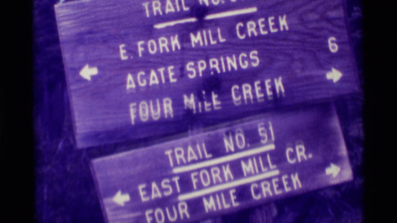 1975 8mm frame from Agate Springs, Montana, showing weathered wooden Trail No. 51 direction signs with arrows and creek names.