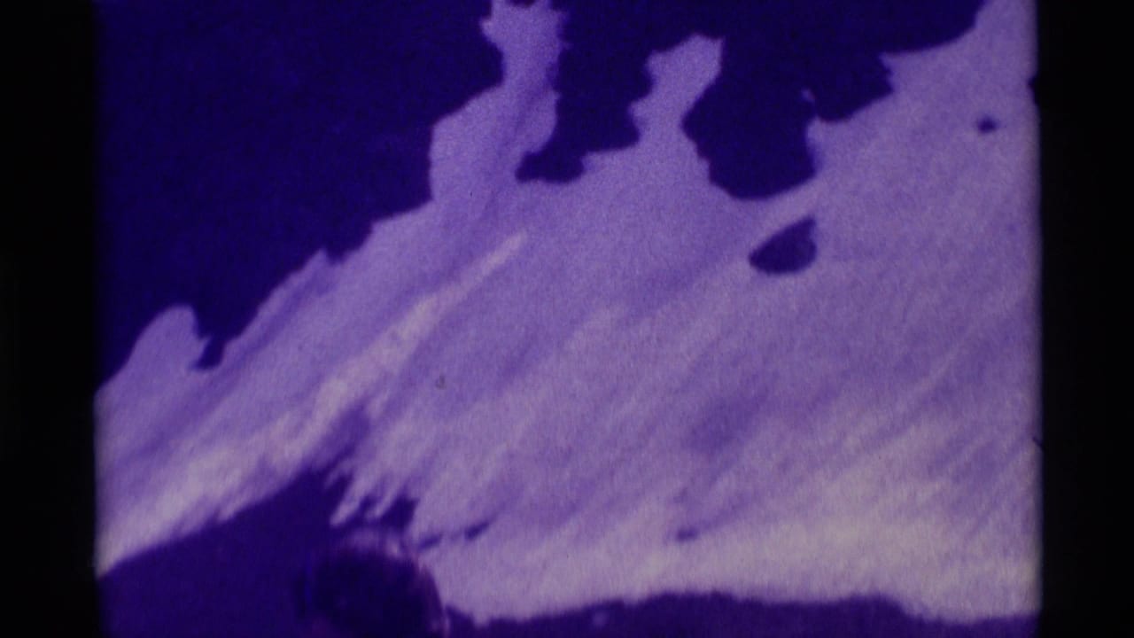Purple-tinted 8mm frame showing snow and dark rock on a steep mountain slope in the Montana hiking clip.