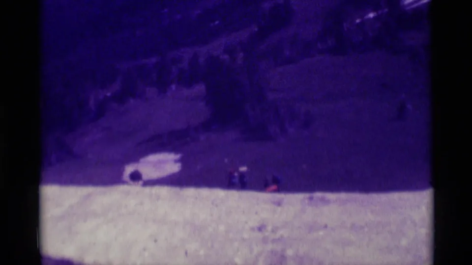 A purple-shifted 8mm frame showing distant hikers near a pale mountainside trail in the Agate Springs, Montana clip.