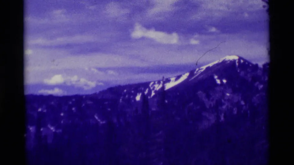 A snow-patched mountain ridge in the Agate Springs, Montana area is filmed from a distance with visible 8mm grain and color fading.