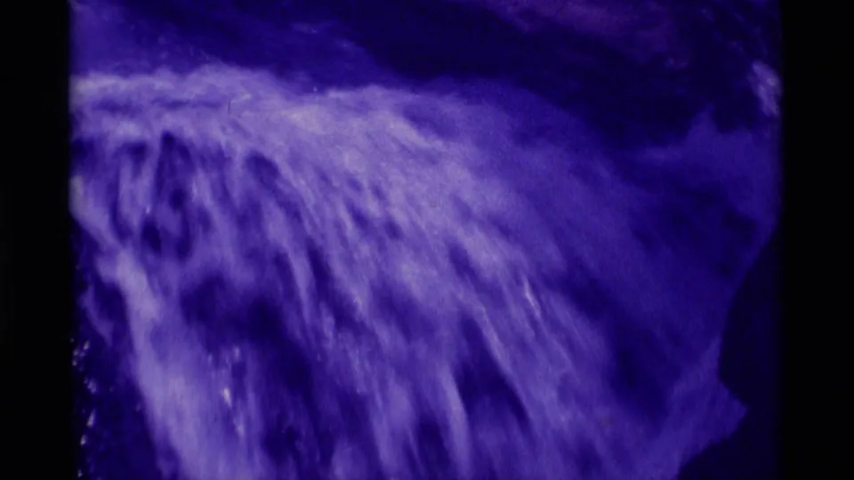 Close 8mm frame of fast-moving waterfall water in Montana, softened by motion blur and strong purple film fading.