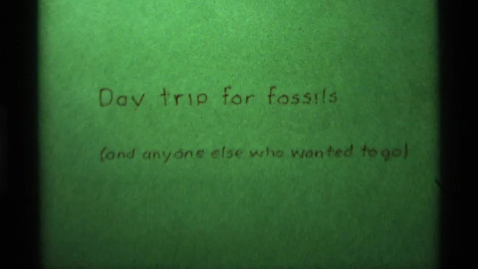 Green 8mm title card from the 1975 Agate Springs, Montana footage, showing handwritten text about a fossil day trip.