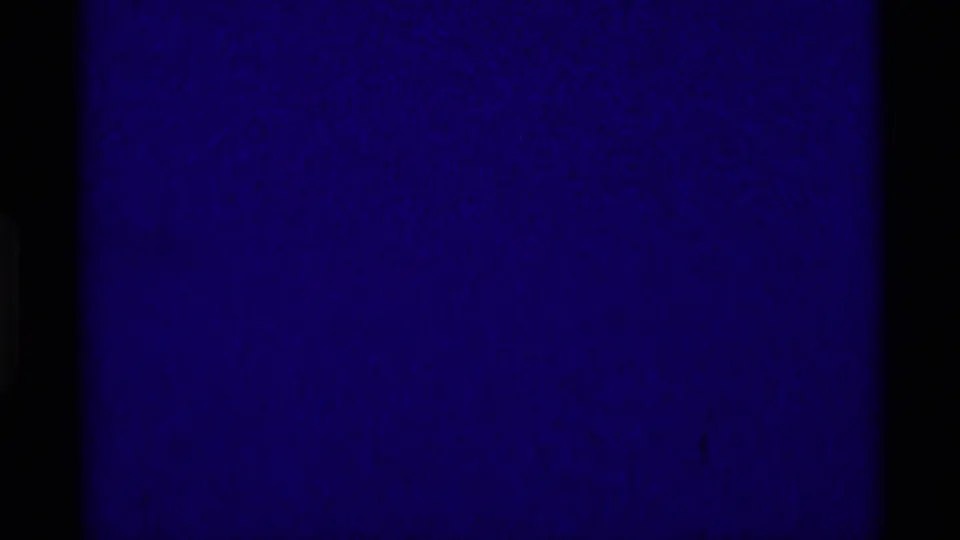 Dark transitional 8mm frame with heavy purple-blue tint, visible grain, and little discernible landscape detail.