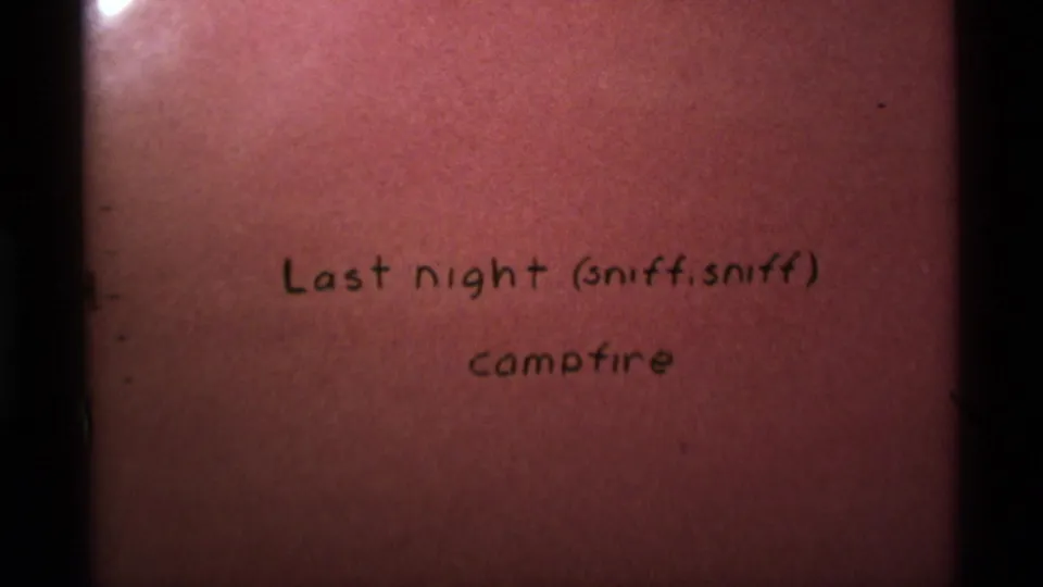 1975 8mm home-movie intertitle for a campfire scene in Agate Springs, Montana, with reddish tint and gate edges.