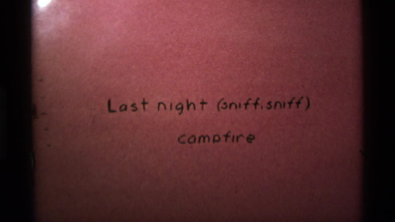 Handwritten campfire intertitle remains centered on reddish film.
