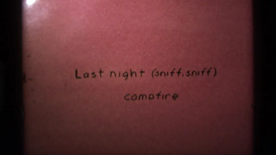 Reddish 8mm title card with handwritten text introducing last night's campfire, likely from the same Montana home movie.