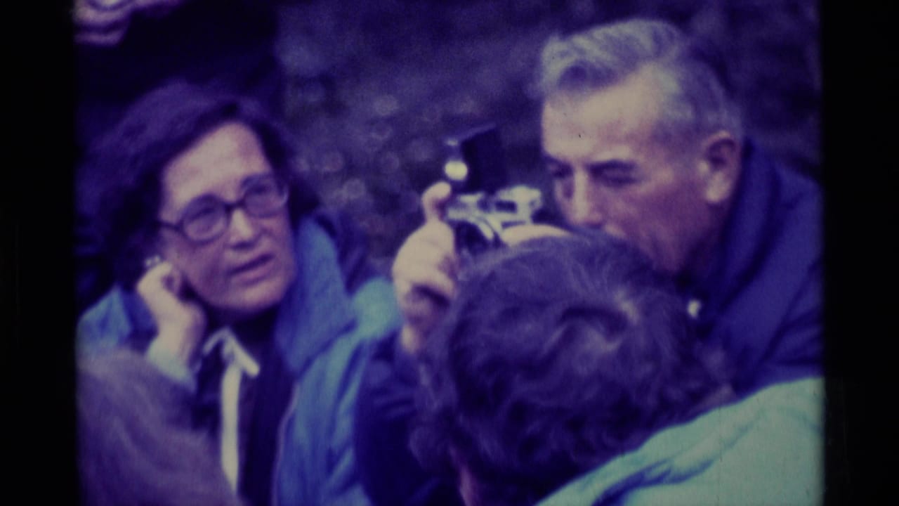 1975 Agate Springs, Montana 8mm frame of adults sitting close together outdoors while one man holds a small camera.