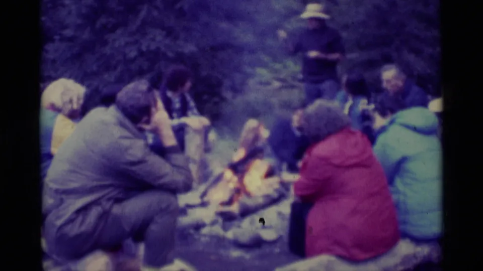 1975 Agate Springs, Montana home-movie frame of adults gathered around a campfire in colorful jackets.