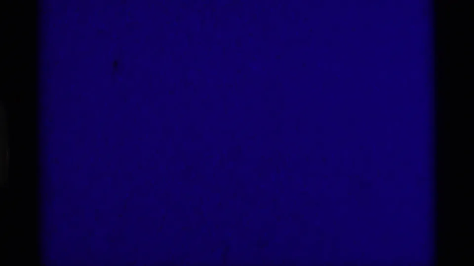 1975 8mm home-movie frame showing a largely blank blue-purple exposure area with grain and dark film borders.