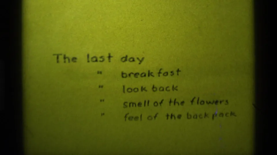 1975 8mm frame from Agate Springs, Montana showing a handwritten final-day memory list on yellow-green tinted film.