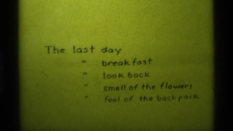 1975 Agate Springs home-movie frame showing the handwritten last-day list before the camping group appears.