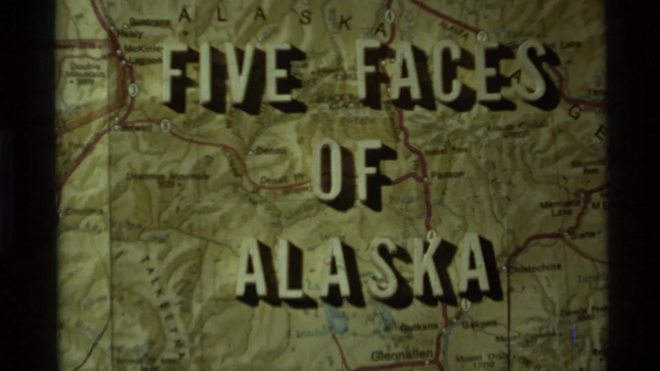 Warm, grainy 8mm title-card frame for an Alaska travel reel, with the title centered on a printed map.