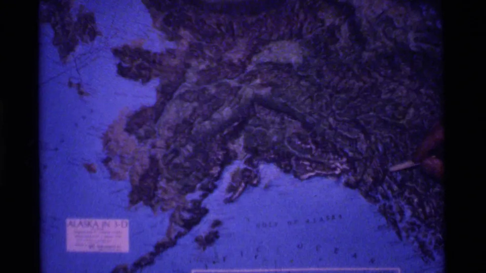 Projected Alaska relief map in blue and purple tones, with the "ALASKA IN 3-D" label visible and a pointer at the right edge.