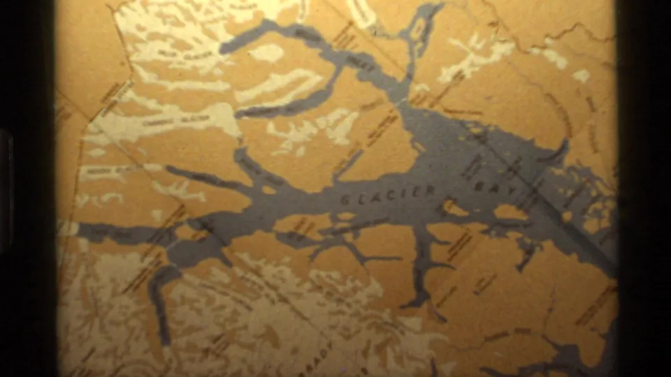 1977 Alaska 8mm close-up of a printed Glacier Bay map, with branching waterways and surrounding landforms visible.
