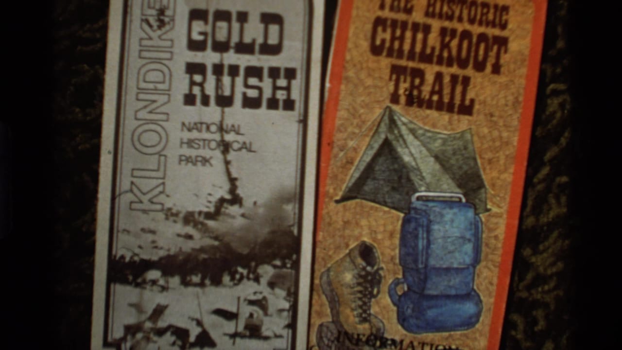 1977 Alaska 8mm frame showing printed tourist brochures for Klondike Gold Rush National Historical Park and the Chilkoot Trail.
