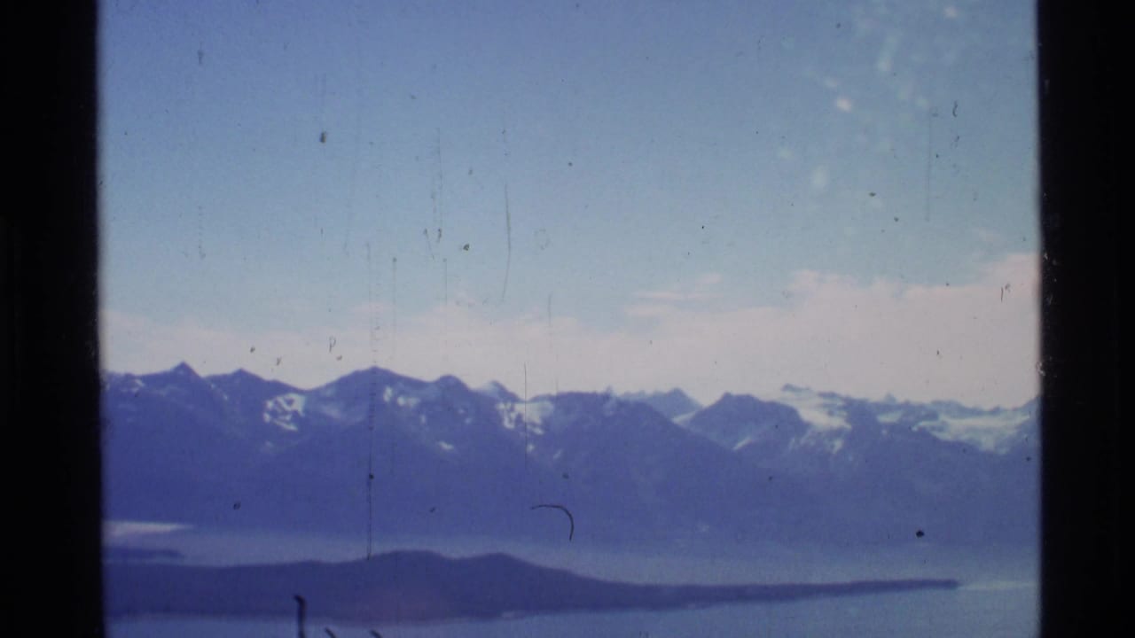 Distant mountain ridges and blue water framed by aircraft window edges.