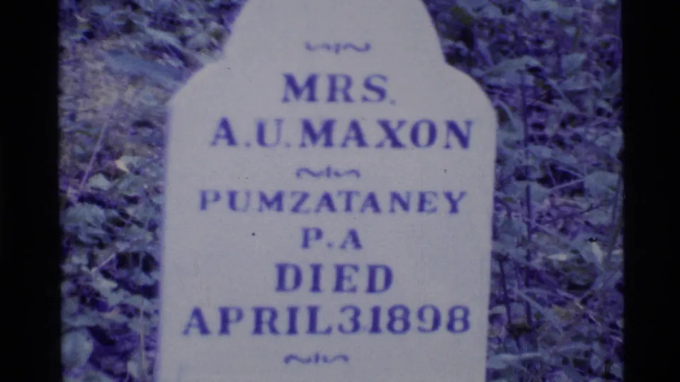 Close 8mm frame of a pale cemetery headstone with readable Mrs. A.U. Maxon and April 3, 1898 inscription.