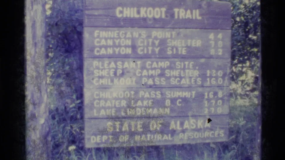Close 8mm view of the Alaska Chilkoot Trail sign, including Finnegan's Point, Canyon City, and Chilkoot Pass Summit listings.