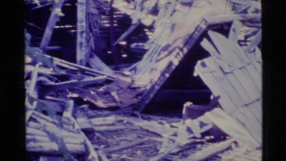 1977 Alaska 8mm frame showing a closer view of collapsed timber and scattered debris in a wooded setting.
