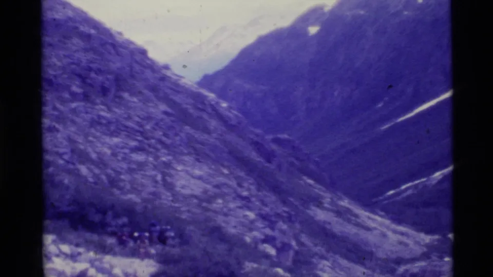 1977 Alaska 8mm view across a steep mountain valley with snow traces and deep blue color shift.