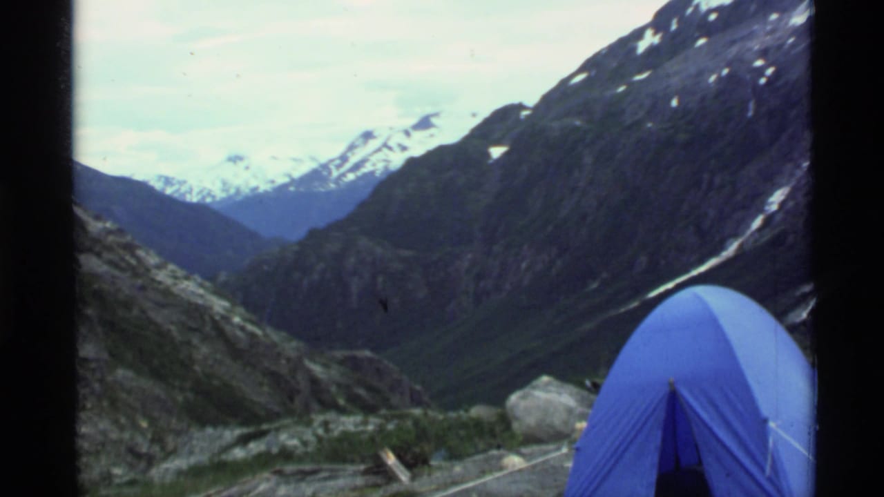 Blue tent at the right edge of a rocky mountain valley view.