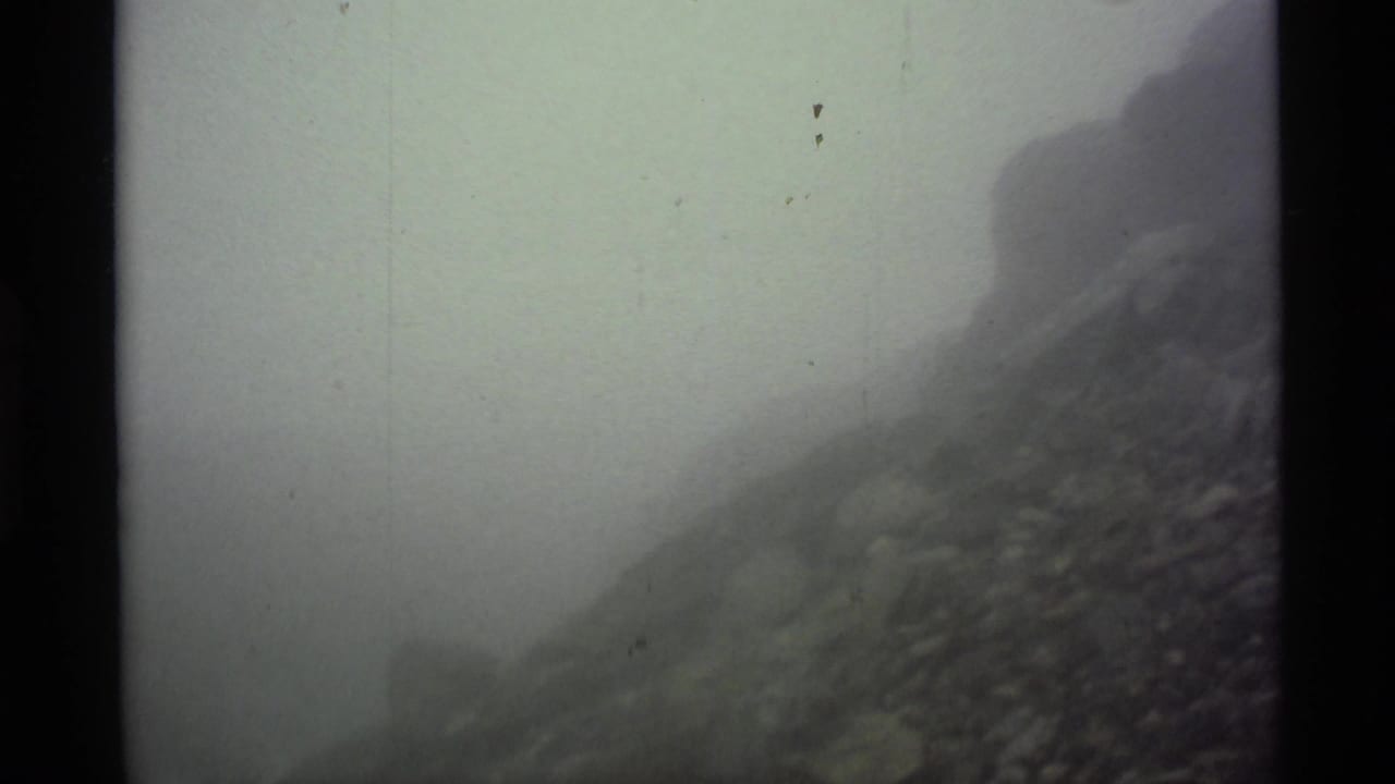 Fog-covered rocky mountain slope with dark 8mm frame borders.